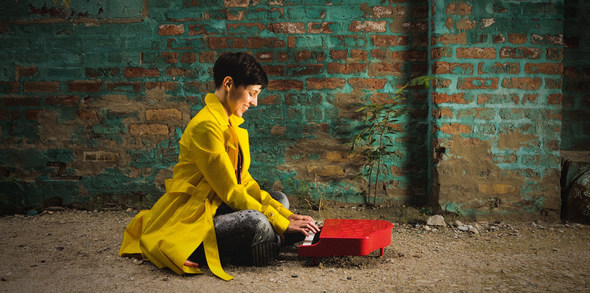 Diana Lawrence wearing a yellow coat, sitting at a red toy piano